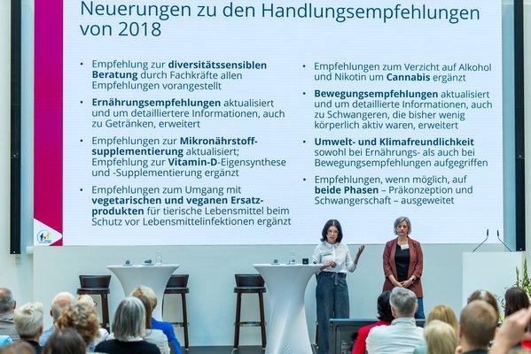 Dr. Katharina Reiss und Dr. Felizitas Alaze-Hagemann präsentieren auf der Bühne die Neuerungen der Handlungsempfehlungen.