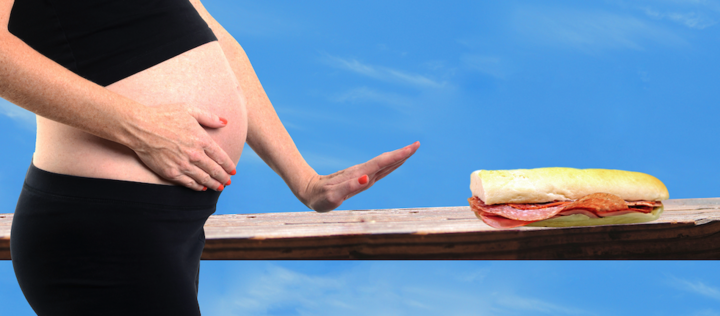 Schwangere macht ablehende Geste zum Salami-Baguette