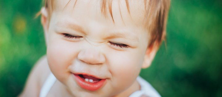 Baby draußen im Grünen zeigt seine ersten Milchzähne