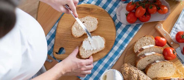 Schwangere schmiert ein Brot mit Frischkäse