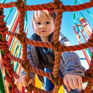 Baby klettert im Freien auf Klettergerüst