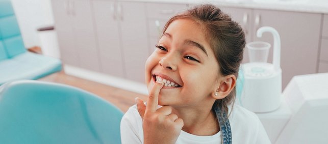 Kleines Mädchen zeigt in der Zahnarztpraxis stolz die Zähne