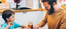 Vater und Sohn essen gemeinsam am Tisch sitzend. 