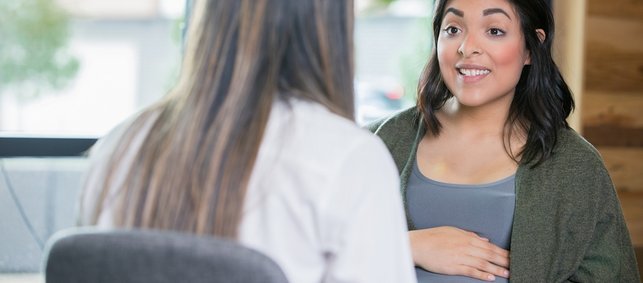 Lächelnde Schwangere hört Hebamme zu