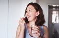 Junge Frau mit braunen Haaren und Sommersprossen hält ein Glas Wasser in der einen hand und führt mit der anderen eine Tablette zu ihrem Mund.