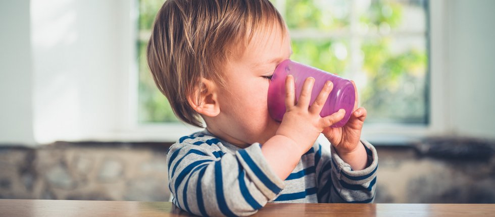 Kleinkind trinkt aus Plastikbecher