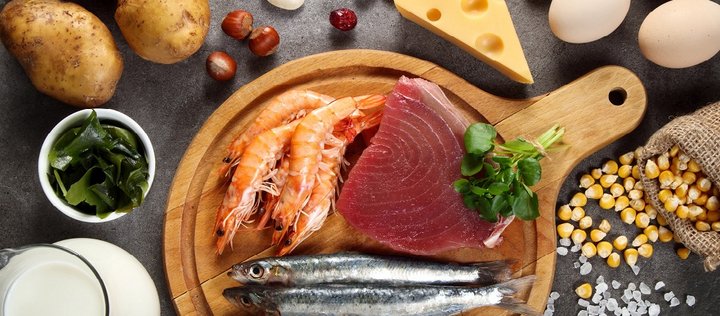 Auf einem schwarzen Tisch liegen verschiedene jodreiche Lebensmittel wie Fisch, Eier und Milchprodukte