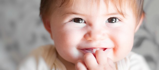 Grinsendes Baby mit Haaren und den ersten Milchzähnen