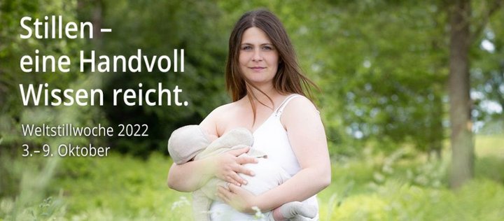 Sanf lächelnde Frau hält Baby auf Wiese im Arm. Im Hintergrund sind Bäume zu sehen.