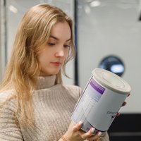 Frau liest Text auf Packung von Säuglingsnahrung