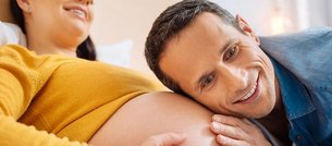 Mann horcht an schwangerem Bauch