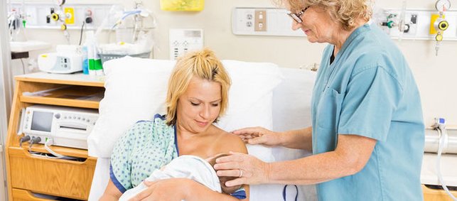 Krankenschwester unterstützt Mutter beim Stillen in Klinik