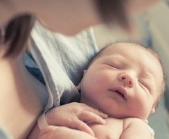 Frau hält Neugeborenes im Krankenhaus