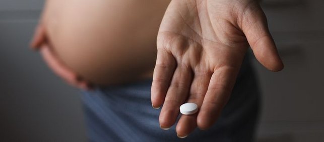 Schwangere mit Tablette in Hand