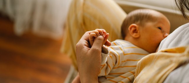 Frau stillt und hält die Hand ihres Babys