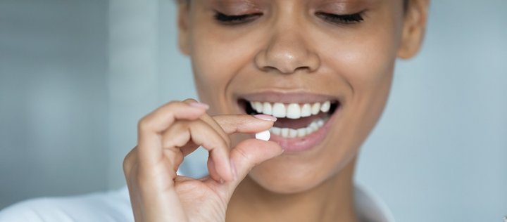 Frau lächelt und nimmt eine Tablette