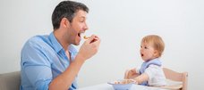 Mann isst Babybrei vor Baby