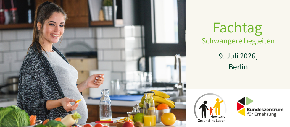 Schwangere steht in ihrer Küche und probiert Obst und Gemüse.