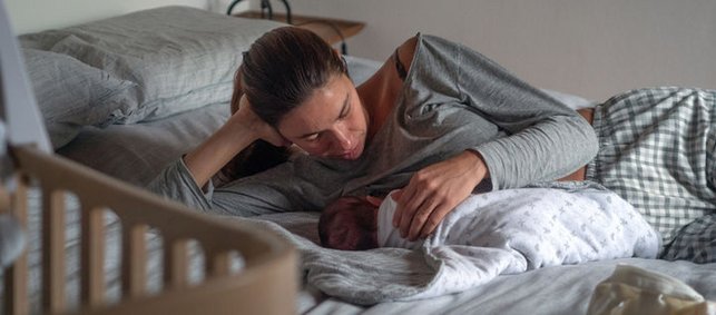 Frau stillt Baby im dunklen Schlafzimmer