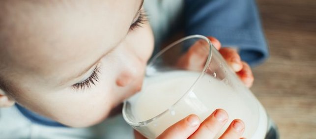 Baby trinkt ein Glas Milch