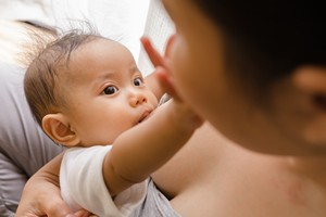 Baby greift nach Mutter als es gestillt wird