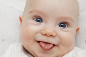 Lächelndes Baby streckt Zunge raus