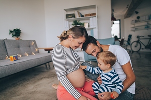 Baby und Papa schauen auf Mamas schwangeren Bauch