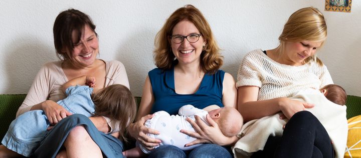 Drei Frauen lachen und stillen auf Sofa