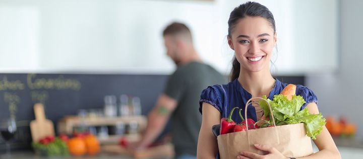 Frau mit Einkauf und Mann in Küche