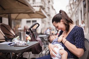 Frau stillt Baby in Cafe