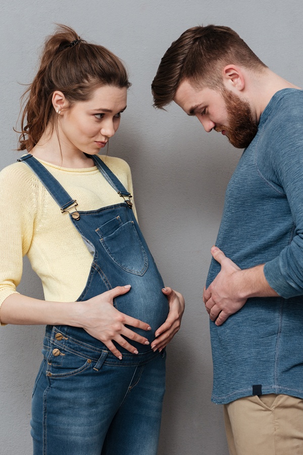 Schwangere und Mann halten ihre Hände auf den Bauch