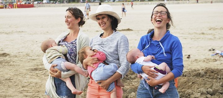 Drei lachende Frauen stillen am Strand